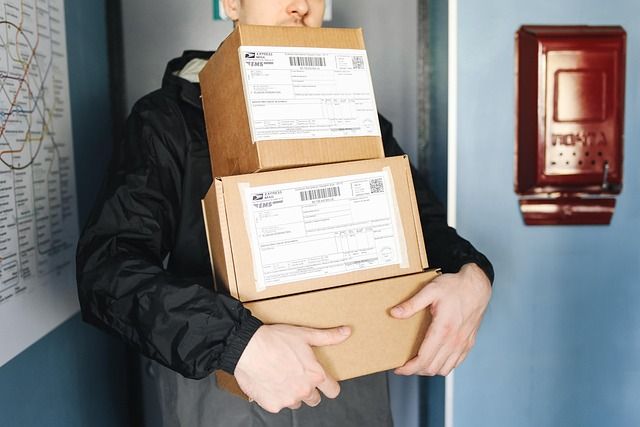 A delivery man handing cardboard boxes to a person.