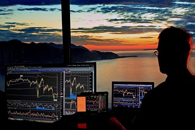Stock market charts and financial data displayed on multiple trading screens.