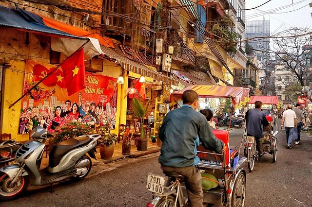 Tourists riding happily on a rickshaw through a city.