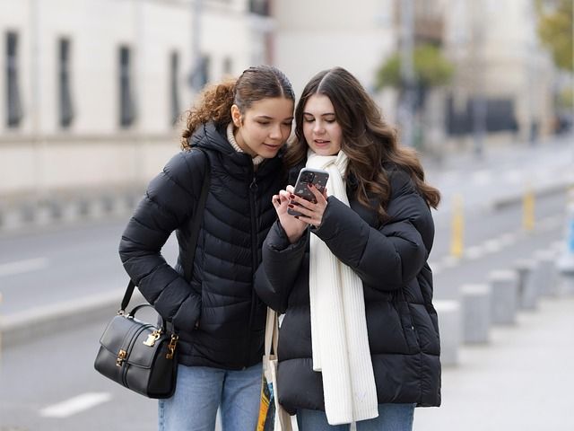 A person holding a smartphone displaying a social media news feed.