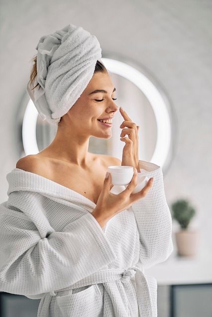 A woman applying skincare lotion on her face at night