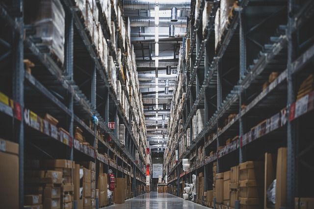 Boxes of office supplies stacked on shelves in a warehouse storage room.
